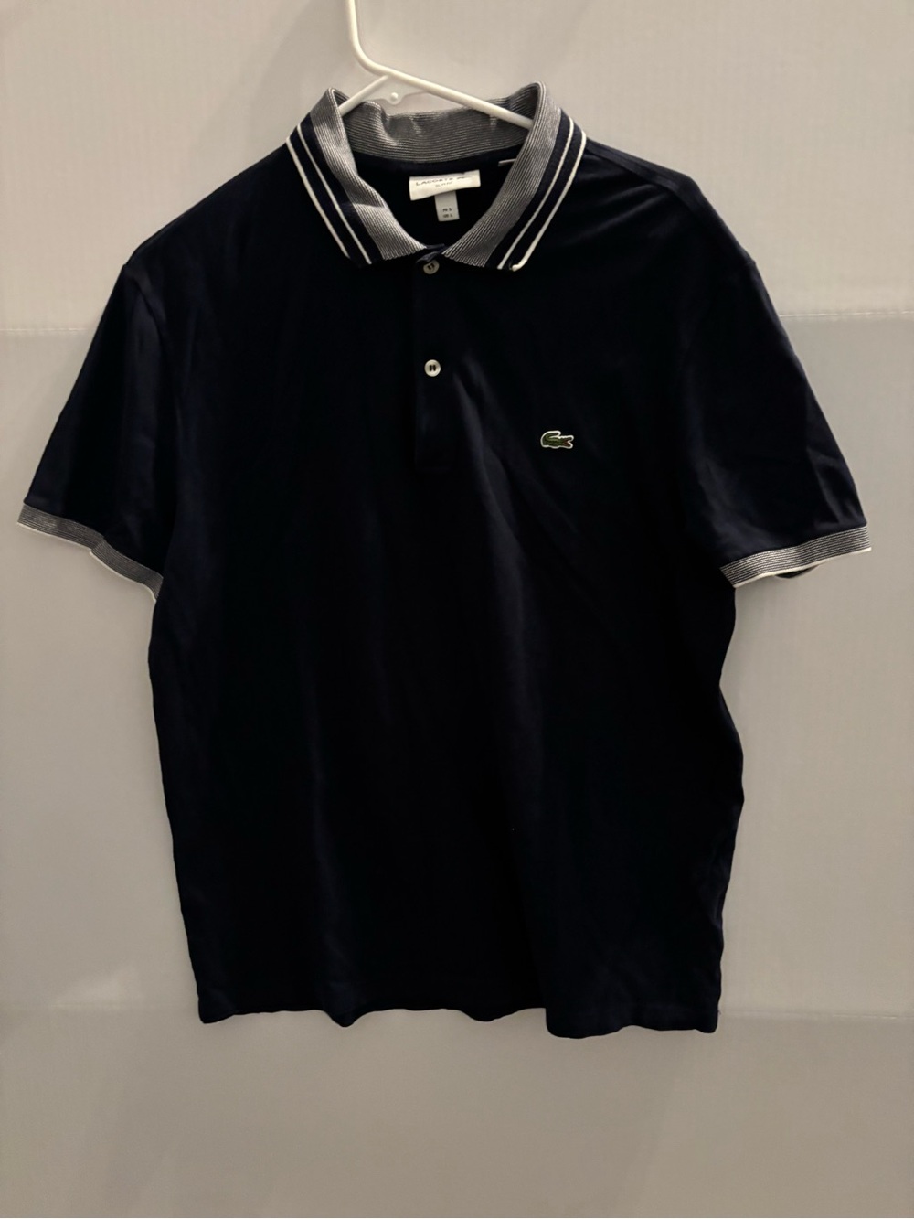 Lacoste Navy Polo with white and blue stripes trim.